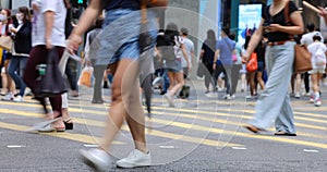 Blurred Busy crowds of men and women or Commuters Crossing Street in Central, Hong Kong, with Crosswalk yellow lines. zebra yellow