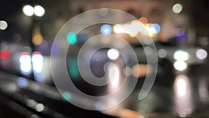 Blurred car lights bokeh in the evening city. Defocused headlights and street lighting at night. Moving bokeh circles of