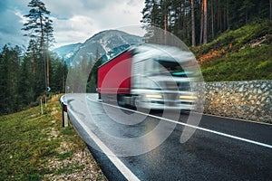 Blurred car in motion on the road in green forest in rain