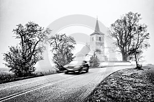 Blurred car motion on the road with old church at background