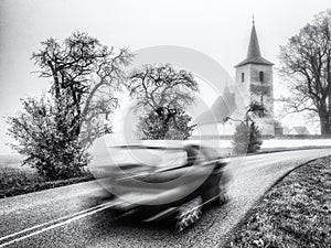 Blurred car motion on the road with old church at background