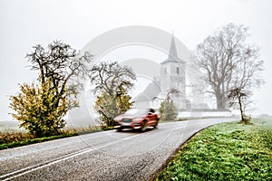 Blurred car motion on the road with old church at background