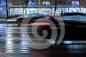 Blurred cars driving fast on wet city road during rain