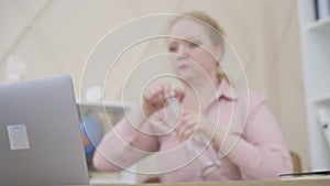 Blurred Caucasian woman taking bottle of water and drinking. Busy senior businesswoman feeling thirsty as working online