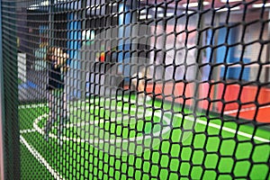 Blurred children are playing behind the net at indoor playground in activity park