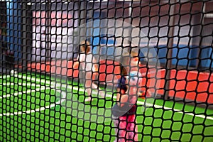 Blurred children are playing behind the net at indoor playground in activity park