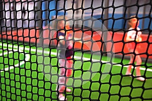 Blurred children are playing behind the net at indoor playground in activity park