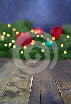 Blurred Christmas, New Year background with defocused fir tree branches, toys, blurry lights. Wooden board with small clear space