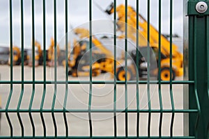 Blurred Construction Vehicles Behind a Fence