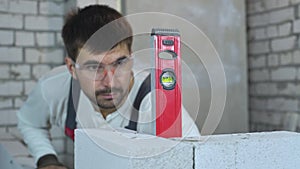 Blurred construction worker checking evenness of wall with bubble level