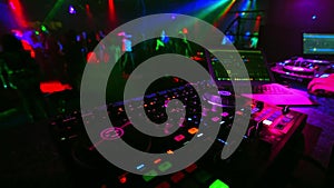 Blurred dancing crowd of people in a nightclub at party with a DJ music mixer