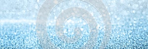 Blurred defocused bokeh banner with Christmas lights and silver glitter sparkles.