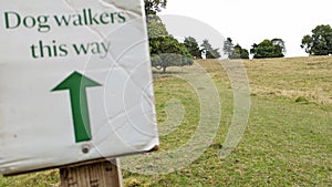 Blurred dog walkers this way sign in the countryside