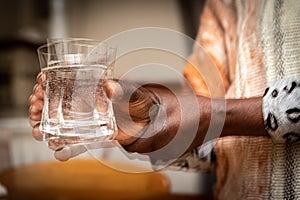 Blurred effect on the hands of a Parkinson`s disease patient with tremors while holding a glass