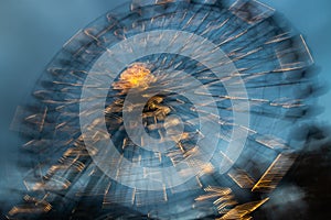 Blurred ferris wheel in motion at the amusement park, night illumination. Long exposure