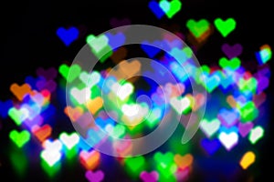 Blurred festive background with defocused colourful glitter formed a heart, bokeh in a shape of a heart. Original photographic