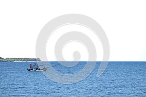 Blurred a fishing boat sailing in a deep blue sea with white sky background