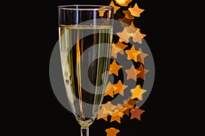 Blurred focus of a glass of sparkling wine with golden star shape bokeh lights