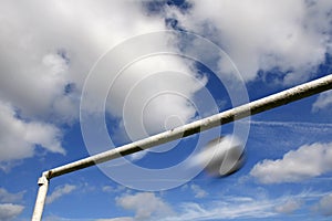 Blurred football and goalpost against a cloudy sky