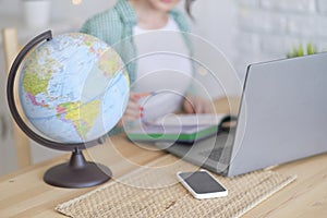 blurred globe in the foreground. in the background a woman works at a laptop, illustration of an international company