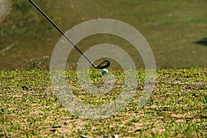 Blurred golf club and golf ball close up in grass field with sunset.