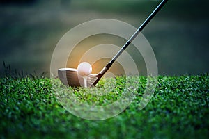 Blurred golf club and golf ball close up in grass field with sunset. Golf ball close up in golf coures