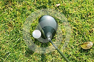 Blurred golf club and golf ball close up in grass field with sunset.