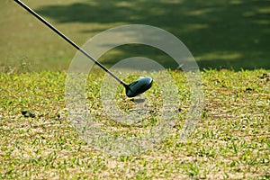 Blurred golf club and golf ball close up in grass field with sunset.