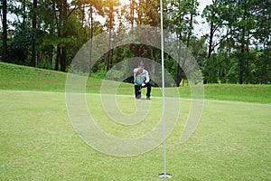 Blurred golf player at the putting green hitting ball into a hole. Golfer playing golf in beautiful golf course in thailand