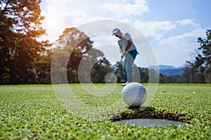 Blurred Golfer putting ball on the green golf, lens flare on sun set evening time. Golfer action to win after long putting golf