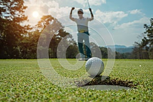 Blurred Golfer putting ball on the green golf, lens flare on sun set evening time. Golfer action to win after long putting golf