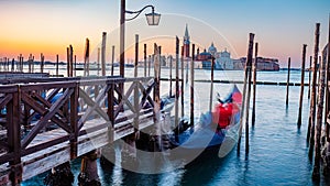 Blurred Gondolas at Saint Mark Square pier with San Giorgio di Maggiore Church during sunrise, Venice