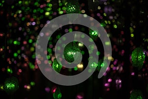 Blurred green purple garlands bokeh light on black