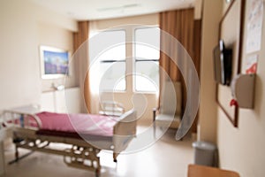 Blurred hospital indoor room with bed and window with lush sunlight