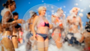 Blurred image of big crowd dancing on the sea beach on summer holiday vacation. People having fun and celebrating.