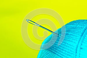 Blurred image of blue thead and needle over yellow background. photo