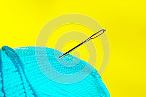 Blurred image of blue thead and needle over yellow background. photo