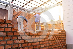 Blurred image of Bricklayer worker installing brick masonry on exterior wall with trowel putty knife on construction site