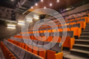 Blurred image of empty theatre or cinema auditorium hall with rows of seats or chairs, defocused