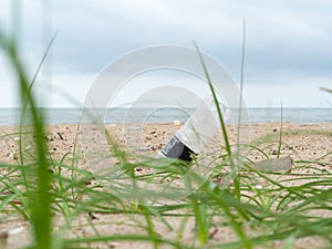 Blurred image of grass. Disposable water bottle (embroidered head in the sand) on the beach, and, sand, sea