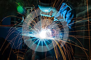 Blurred image of Industrial steel welder using blue helmet and grinder