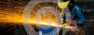 Blurred image of Industrial steel welder wearing jeans and yellow helmet