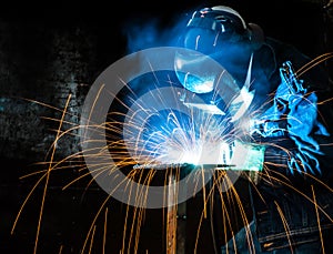 Blurred image of Industrial steel welder at the workplace using blue helmet