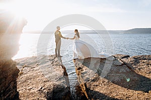 Blurred image of just married wedding couple standing at the cliff near the ocean