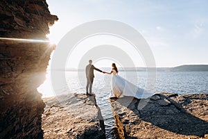 Blurred image of just married wedding couple standing at the cliff near the ocean