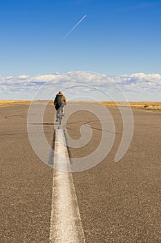 Blurred image of a man cyclist on a sunny summer day cycling in the middle of the road.