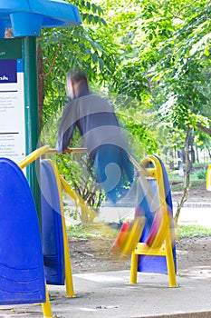 Blurred image of a man exercising on equipment in a park in Thai