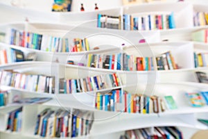 Blurred image of many books on curved bookshelf in library background.