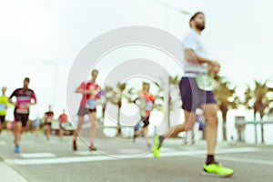 Blurred image of people running in massive marathon on a sunny summer day.