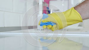 Blurred Image with Person Hands Wearing Protective Yellow Household Gloves Cleaning the Kitchen Furniture